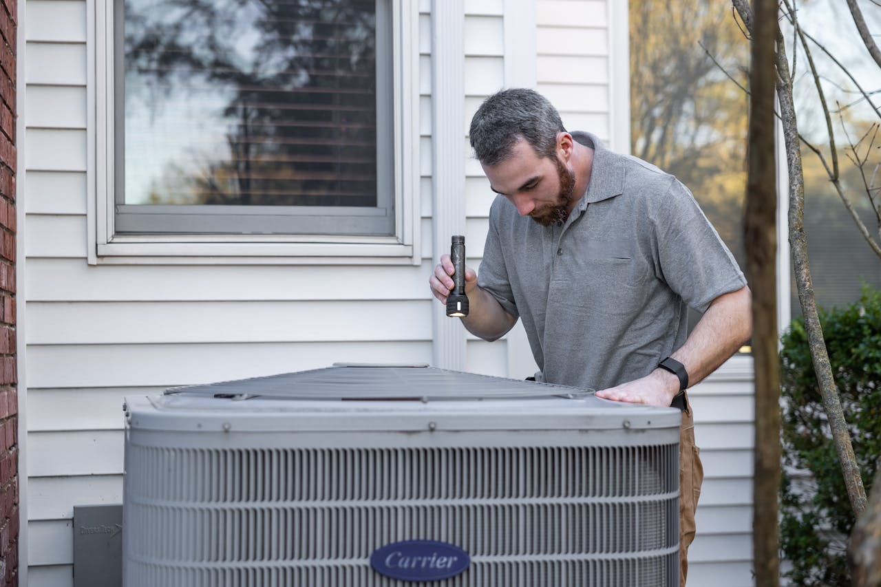 Home A technician inspects an outdoor HVAC unit for maintenance.